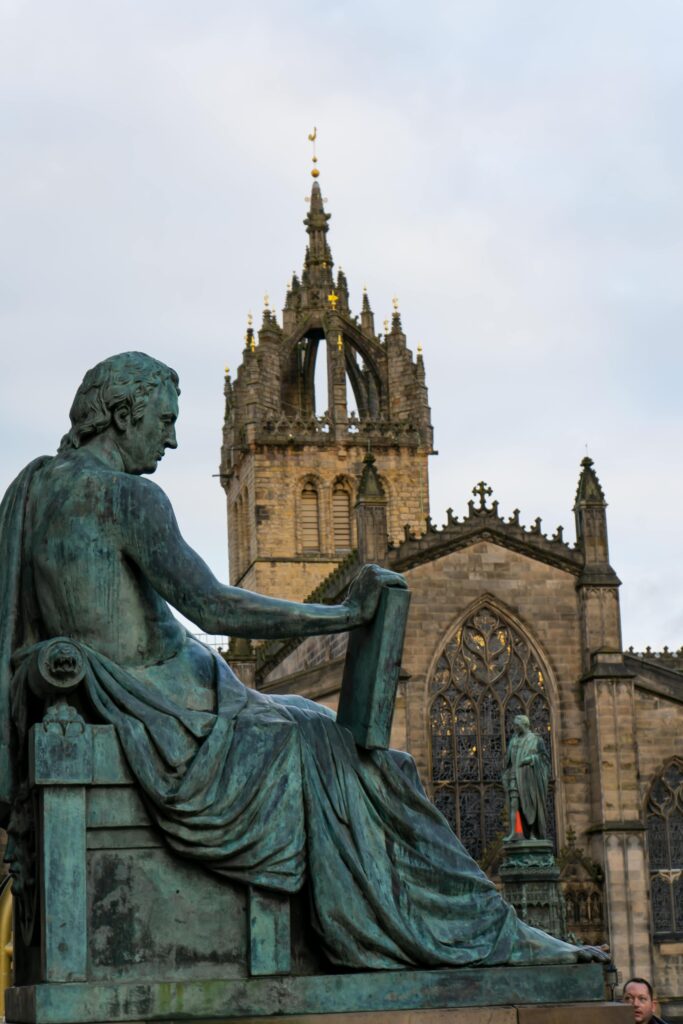 Statue of David Hume with St. Giles' Cathedral in Edinburgh, Scotland.